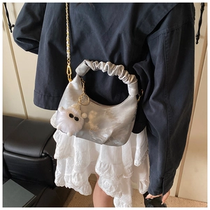 Détail du sac à main plissé argenté avec finition métallique et breloque peluche