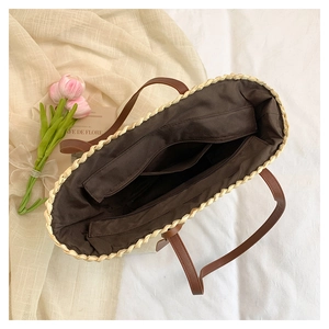 Vue intérieure du sac en paille montrant la doublure sombre et la poche zippée spacieuse