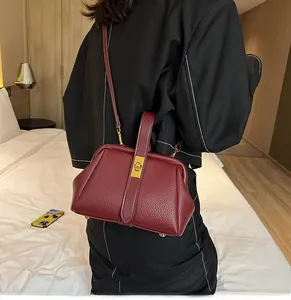 Litchi texture wine red handbag with gold buckle shown on shoulder in bedroom setting