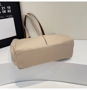 Close-up of beige canvas tote bag with reinforced base and brown contrast handles