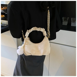 Détail du sac nuage plissé beige avec bandoulière chaîne et accessoire de pompon en peluche