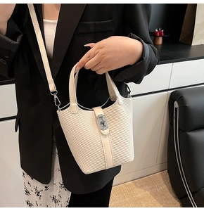 Detail der cremefarbenen gewebten Beuteltasche mit Schloss und Riemen am Modell