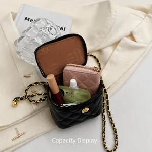 Detail view of black quilted box bag interior showing phone, lipstick and cream storage