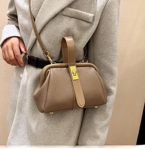 Detail of khaki lychee leather crossbody bag with gold buckle on a stylish wool coat