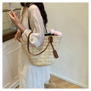 Gros plan d'un grand sac cabas en paille avec bandoulière en cuir et décor de tulipes