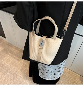 Detailansicht der beigen geflochtenen Eimertasche mit Lederriemen und Drehverschluss