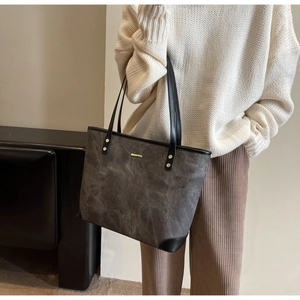 Detailed side view of grey marble tote bag with black straps and golden rivets on model