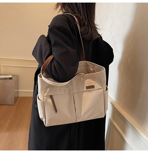Detailed view of canvas tote bag with brown leather handles and side outer pockets