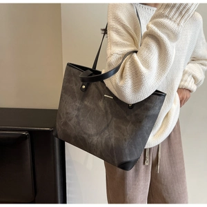 Detail of dark grey tote bag with suede texture and black leather trim for women