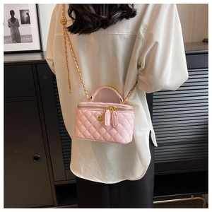 Close-up of pink quilted crossbody box bag featuring a decorative gold rose emblem