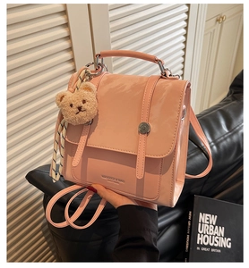 Pink glossy patent leather handbag detail featuring a cute beige plush bear pendant