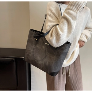 Detail of dark grey marble texture tote bag with gold metal bar and black leather trim