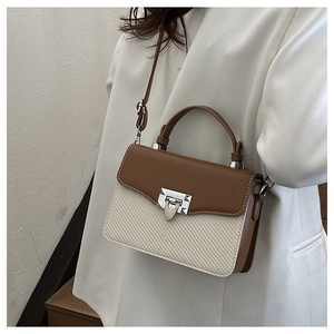 Side view of a woman wearing a color-block handbag with woven texture and metal lock