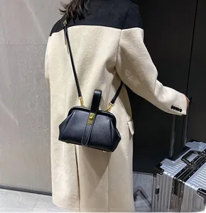 Model wearing a black lychee texture leather handbag with gold hardware and shoulder strap