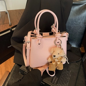 Pink lychee grain bucket bag with knot handles, adjustable strap and cute bear charm