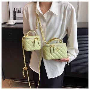 Detail of light green quilted square box bag with gold floral clasp and chain strap