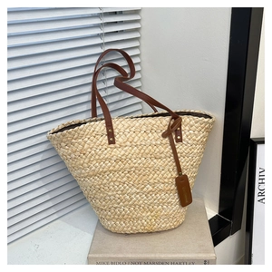 Détail d'un sac cabas en paille tissé avec anses en cuir marron et doublure sombre