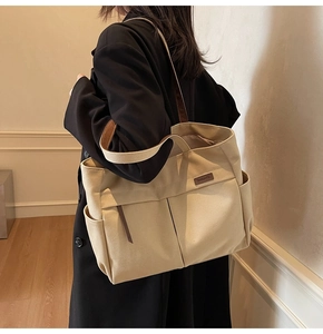 Detail view of large canvas tote bag with brown leather straps and multi-pocket design