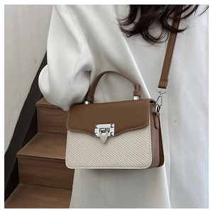 Detail of contrast stitching handbag with woven texture and silver trapezoidal lock