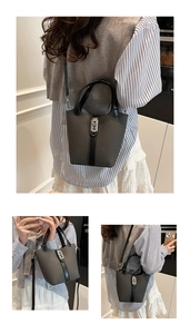 Detail of dark grey woven bucket bag featuring black leather trim and silver metal lock