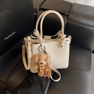 Cream white bucket bag in lychee leather with knotted handle and cute teddy bear charm