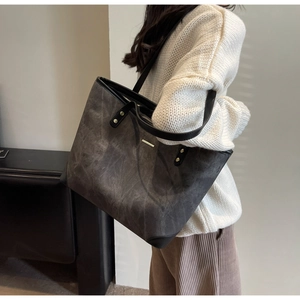 Deep grey tote bag with washed texture and black straps worn by model for daily commute