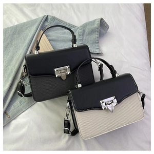 Detailed view of woven texture and silver metallic clasp on contrasting handbags