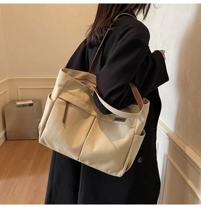 Close-up of canvas tote bag showing deep front pockets and brown leather handles