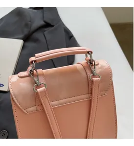 Close-up of pink crossbody bag showing glossy patent leather flap and silver hardware