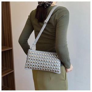 Detail of light blue-grey shoulder bag featuring silver rivets and adjustable strap
