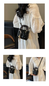 Close-up of black quilted bucket bag with decorative silk scarf and golden pearl charms