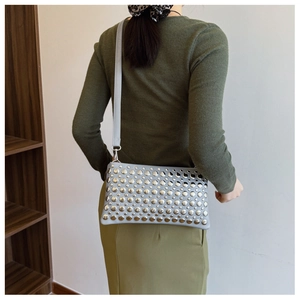 Detail of light blue leather shoulder bag with decorative silver round metal studs