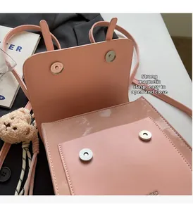 Detailed view of pink leather bag with dual magnetic buckles and plush bear charm