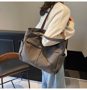 Detail view of large canvas tote bag with multiple pockets and shoulder strap for commute