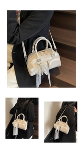 Detail of cream Boston bag with pearl lace bow charm and functional front pockets