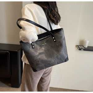 Detail of grey marbled tote bag with black leather corner protectors and gold rivets