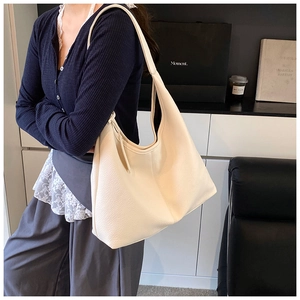 Side view of large off-white lychee texture leather tote bag on a fashion model