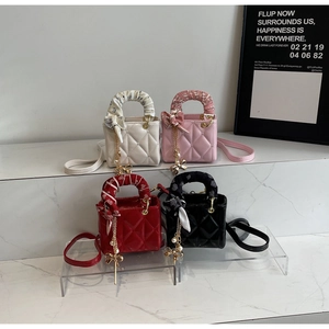 Detail view of quilted mini handbags with silk scarves and butterfly pearl charms in four colors
