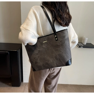 Large capacity vintage tote bag in dark grey matte fabric shown on shoulder of a model