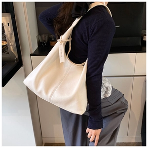 Detailed close-up of a white lychee grain leather tote bag worn as a shoulder bag