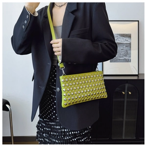 Close-up of mustard yellow leather shoulder bag with metallic silver rivets decoration