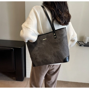 Detail of a large brown tote bag showing matte texture and reinforced leather corners