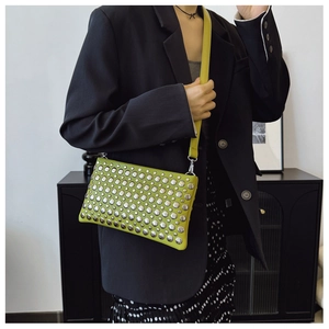 Detail of green shoulder bag with silver studs and metal hardware on model