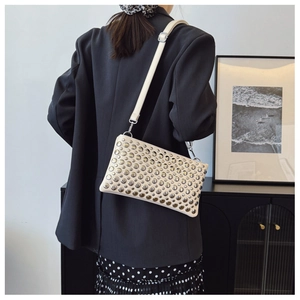 Detailed view of beige PU leather crossbody bag with silver stud embellishments and buckle