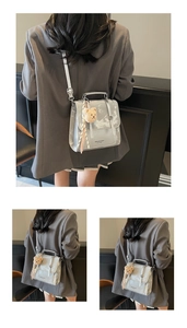 Detail of silver metallic handbag with plush bear charm and striped scarf accessory