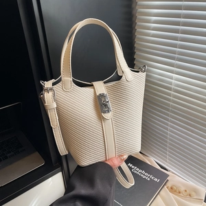 Schicke cremefarbene Flecht-Eimertasche mit Ledergriff und silbernem Verschluss im Büro