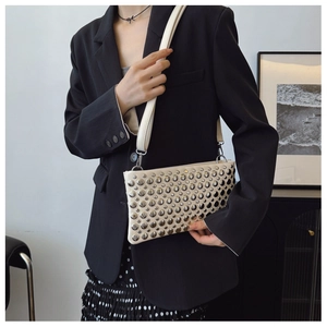 Detail of cream leather shoulder bag featuring silver rivets and adjustable strap