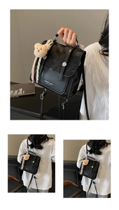 Detail of black textured backpack with silver buckles and a cute plush bear charm