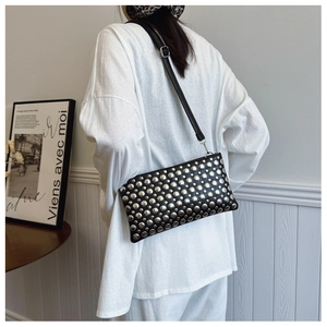 Detail of black rectangular crossbody bag featuring punk style silver stud rivets on the surface