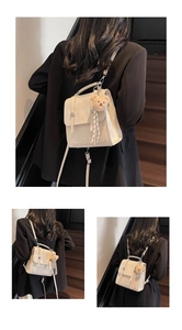 Close-up of beige square backpack with metal buckle and cute bear pendant charm
